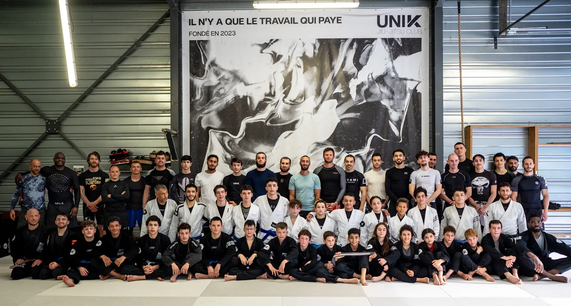 Une cinquantaine d’adhérents UNIK en kimono devant la fresque « Il n’y a que le travail qui paye »